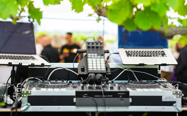 Unmanned dj stand and his headphones and the rest of the equipment in an outdoors party venue.