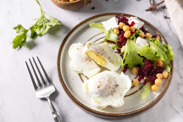 Easter breakfast or brunch. Poached egg and beet salad with spinach, cheese feta, chickpeas on a marble tabletop.