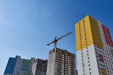 Fototapeta na wymiar Modern new residential concrete high-rises on a background of the sky and construction nearby. Housing construction. Economic housing stock of construction. 