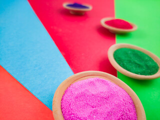 colorful powders for holi or dol on clay pots on occasion of indian festival of colors. happy holi theme shot against multicolor background.