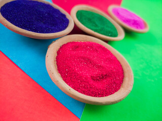 colorful powders for holi or dol on clay pots on occasion of indian festival of colors. happy holi theme shot against multicolor background.