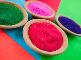 colorful powders for holi or dol on clay pots on occasion of indian festival of colors. happy holi theme shot against multicolor background.