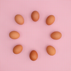 Fresh chicken eggs arrangement in cicrle on pastel pink backgrund. Easter copy space flat lay