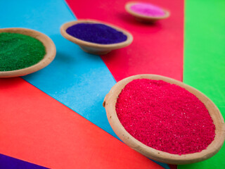 colorful powders for holi or dol on clay pots on occasion of indian festival of colors. happy holi theme shot against multicolor background.