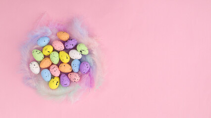 Fototapeta na wymiar Creative Easter composition with colorful eggs on feathers on pastel pink background. Bright flat lay minimal arrangement. Spring holidays copy space