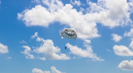 White parachute in sky among clouds, parasailing, paragliding.