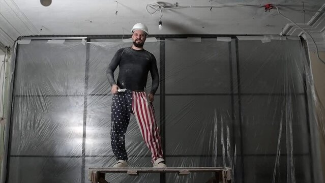 Charismatic young male architect in a white helmet dancing in front of the camera while listening to music