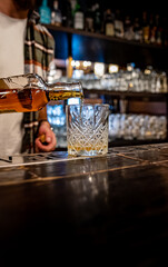 Barman pouring whiskey on glass in bar