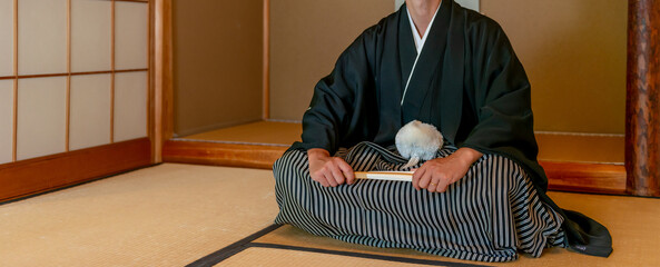 畳の部屋にあぐらで座る羽織袴姿の新郎　