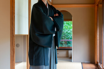 日本家屋の縁側の廊下で腕組みをする羽織袴姿の新郎　結婚式　