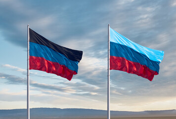 Flags of the Donetsk and Lugansk People's Republics against a cloudy sky. The republics are recognized as independent by Russia on February 21, 2022.