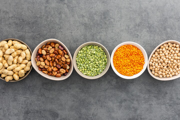 Different types of legumes in bowls, green peas and chickpeas , beans and peanuts and lentils, top view, copy space