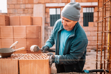 Professional portrait of industrial worker, bricklayer and mason working with bricks and building...