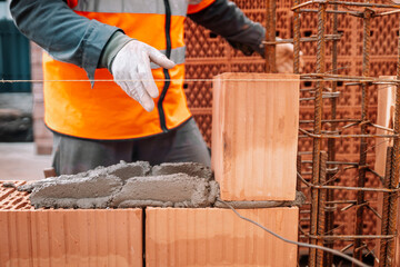 Close up of industrial bricklayer installing bricks on construction site..