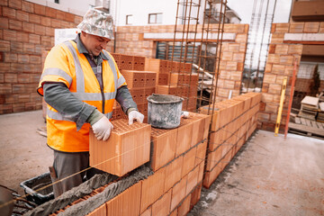 Portrait of Construction worker bricklayer using bricks and mortar for building walls. industry details and construction equipment