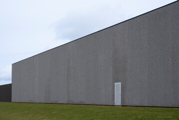 Fototapeta na wymiar a gray wall on a concrete warehouse and a lawn in the foreground