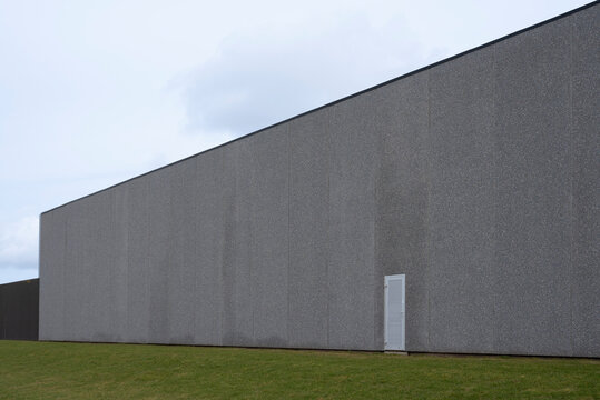 a gray wall on a concrete warehouse and a lawn in the foreground