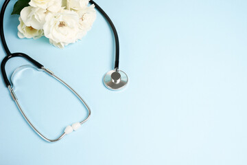 Bunch of white rose flowers and stethoscope on blue background. National Doctor's day. Happy nurse day. Top view with copy space