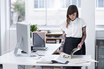 Her tattoo business is flourishing. Shot of a gorgeous young tattooed businesswoman flipping...