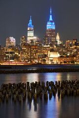 Obraz premium Historic New York skyscrapers illuminated at night from across the Hudson River. Cityscape of West Village and Midtown Manhattan