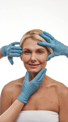Plastic surgeons hands touch face of woman