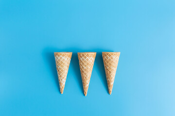 Three sweet crunchy empty ice cream wafer cups on a blue background