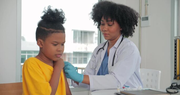 African-American children getting vaccine in clinic or hospital, with hand nurse injecting vaccine to get immunity for protection. vaccine for kids concept.