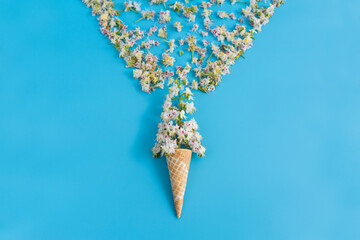 Sweet crispy waffle cup with chestnut flower on blue background. The petals are scattered in the shape of a wineglass