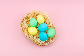 Fototapeta na wymiar Basket of colorful Easter eggs on pink background