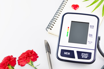 Doctor's day. Digital blood pressure monitor, notepad, pen on a white background with copy space. The concept of medical examination, health control and blood pressure monitoring. Doctor's workplace
