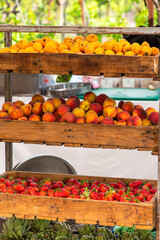 Fruit cart of loquats, peaches, strawberries and artichokes piled in wooden crates.