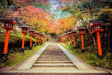 Fototapeta na wymiar A lantern lined path with stairs leading up the the Kurama-dere Temple north of Kyoto, Japan on a fall morning.