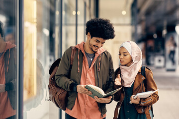 Happy Muslim student and his female friend going through notes after the lecture at campus.
