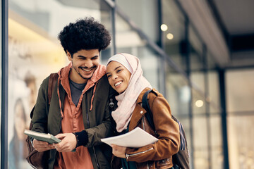 Cheerful Middle Eastern university couple laughing and having fun outdoors at campus.