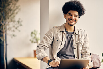 Happy Islamic college student uses laptop and looking at camera.