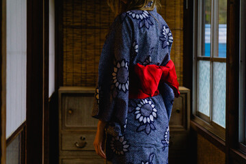 Woman wearing a blue yukata tied with a red bow in a traditional Japanese house