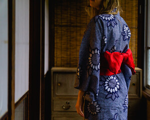 Woman wearing a blue yukata tied with a red bow in a traditional Japanese house