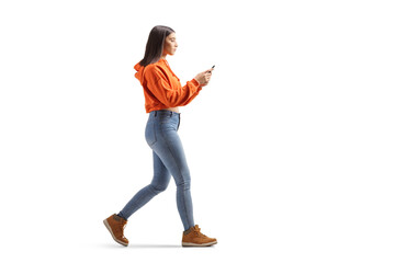 Fototapeta Full length profile shot of a tredny young female walking and using a smartphone obraz