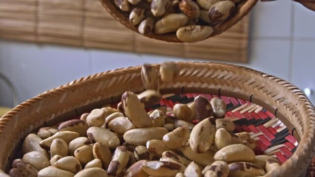 Pouring fresh organic Brazil nuts into a wicker basket in slow motion.