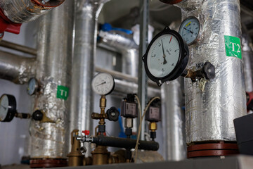 Closeup of manometer, pipes and faucet valves of heating system in a boiler room