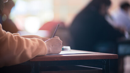 Student taking exam while wearing face mask due to coronavirus emergency. Young woman sitting in...