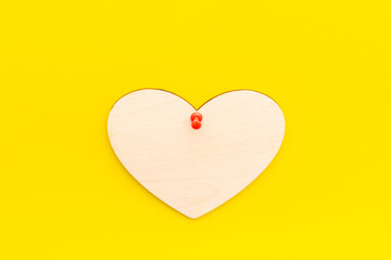 wooden heart on a yellow background pinned with a button