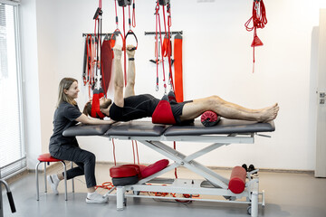 Rehabilitation specialist doing active treatment on suspension straps to a male patient. Concept of...