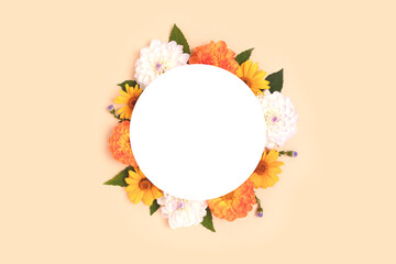 Wreath made of dahlia and arnica on a beige background. Flower round frame with copyspace. Nature concept.