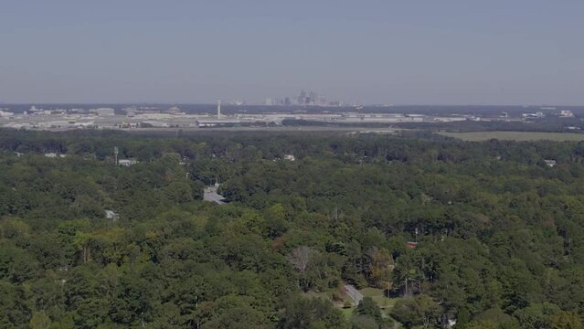 Drone drop down view of atlanta airport behind trees
