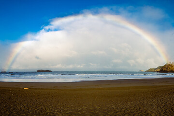 Full length rainbow stretching from Pewetole Island out in to the Pacific Ocean.  Photographed at Trinidad State Beach, Trinidad California, USA.