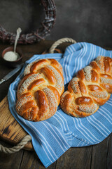 Sweet braided buns with sesame seeds on a blue kitchen towel. Sweet yeast pastry