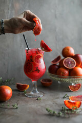 Blood orange juice cocktail with thyme and crushed ice in a stemmed glass. Cold refreshing citrus drink