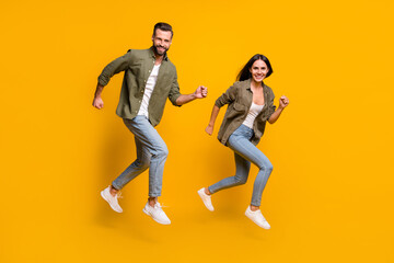 Fototapeta na wymiar Full length profile side photo of young husband wife fast rush motion runner jumper isolated over yellow color background
