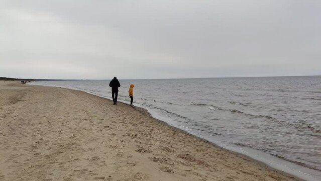 Little girl and adult man walk on the seaside. 